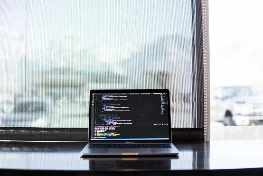 laptop on a desk displaying code on the screen