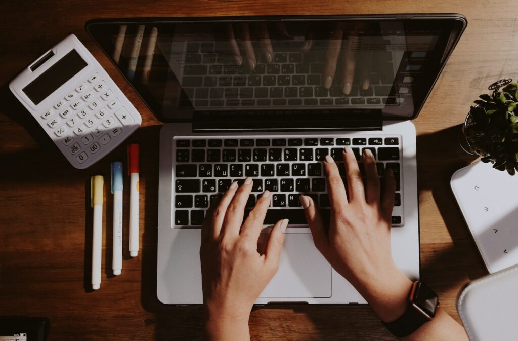 Table with a calculator and typing on laptop keyboard