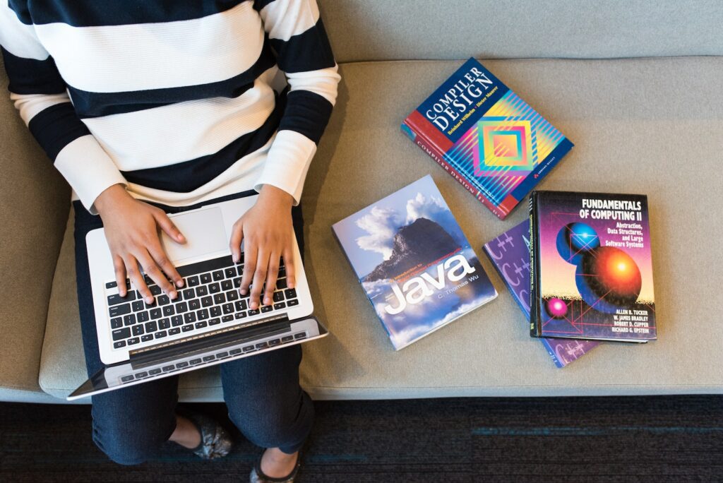 Person on laptop with programming books